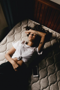 A woman lying down on a mattress due to intense back pain.